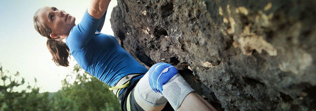 Frau beim Klettern mit Bandage am Knie